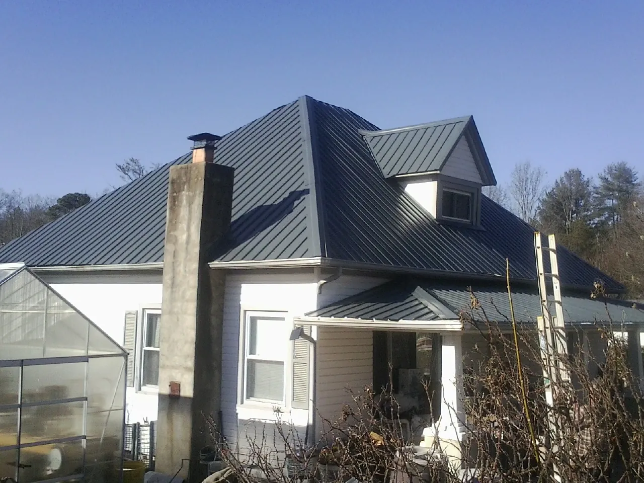 Dark blue standing seam metal roof on a white farmhouse with dormer — Slate & Tile Roof Repair by Roofing Brothers in Downers Grove