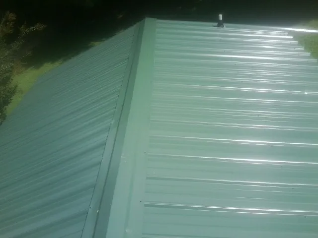New green metal panels meeting at the ridge of a roof — Flat Roof Repair work by our crew in Downers Grove