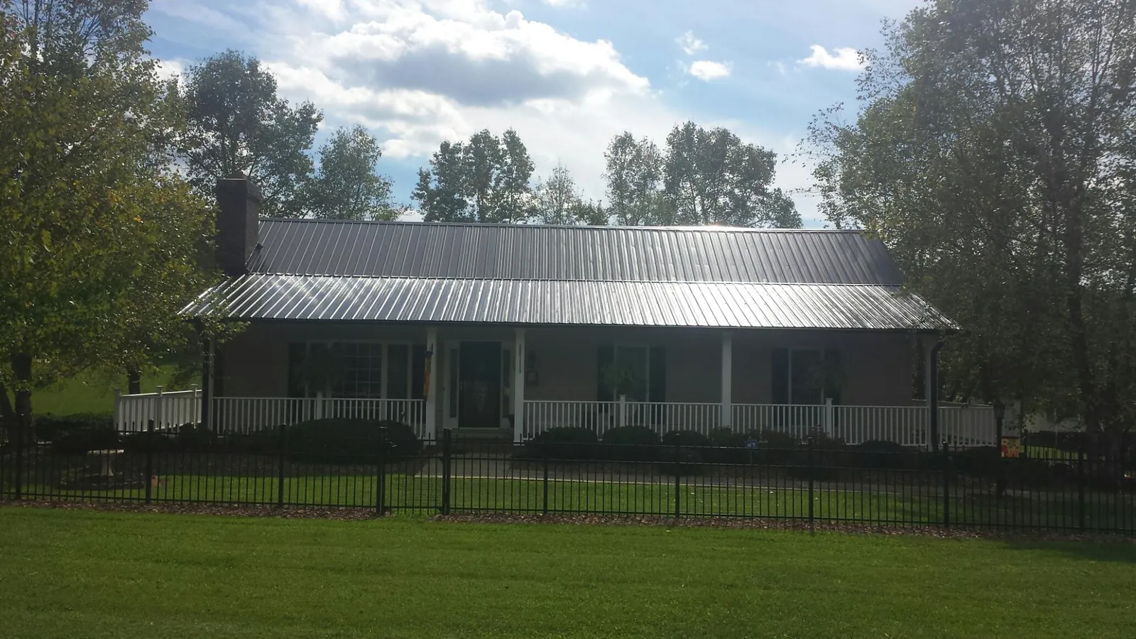 Gray metal roof on a brick ranch with a full width front porch — Gutter Guard Installation work by our crew in Downers Grove
