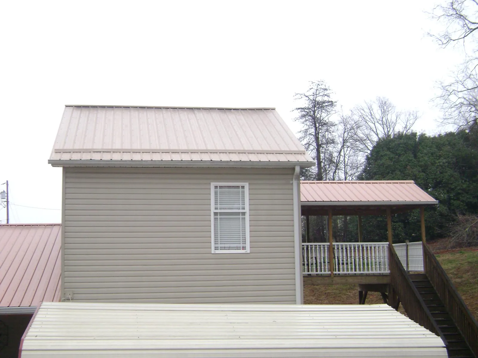 Tan metal roofs on a two story addition and attached porch, from a Roof Replacement job in Downers Grove